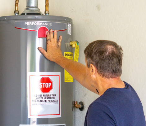 Man inspecting a water heater for performance, highlighting importance of appliance maintenance and replacement.